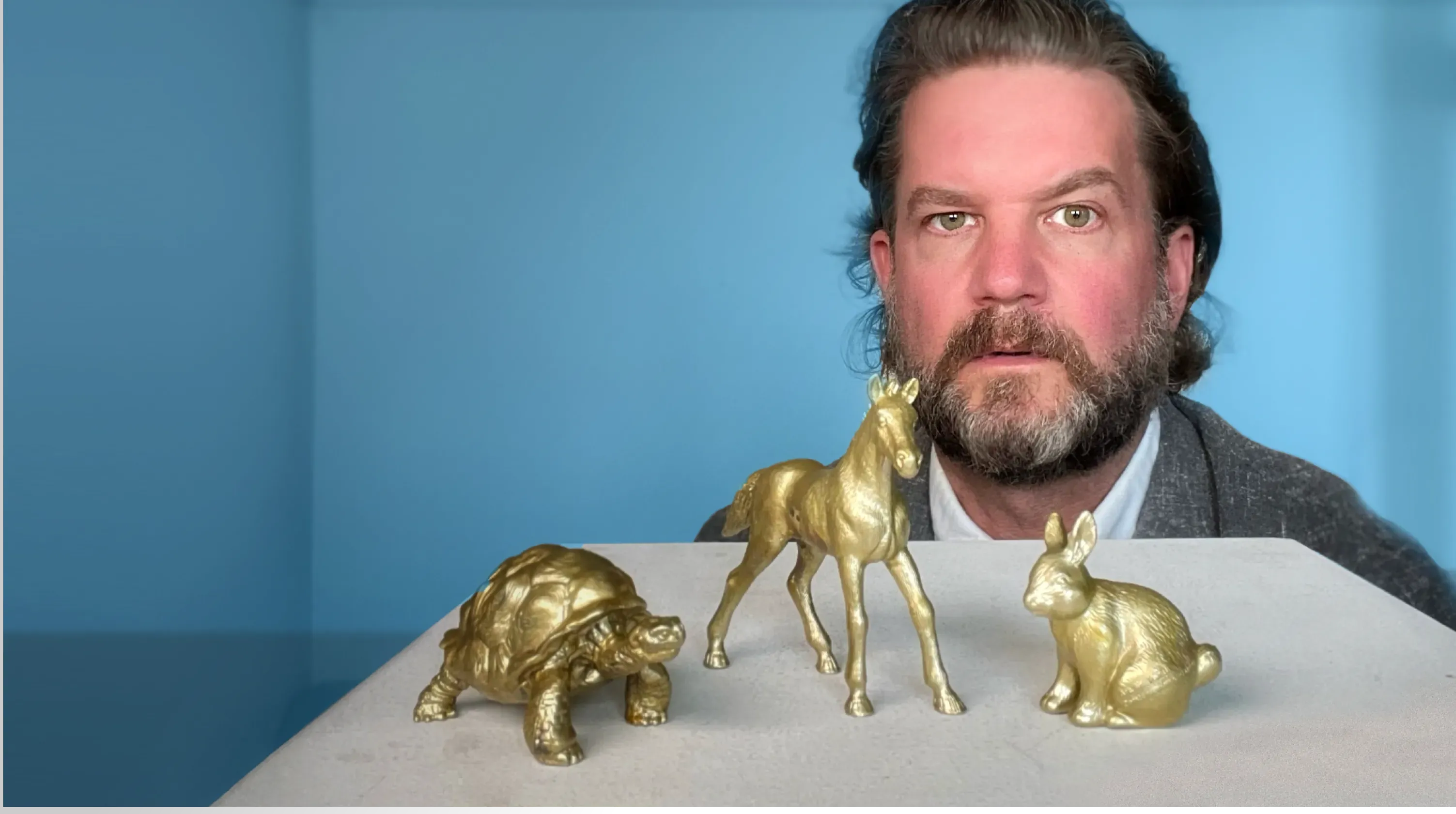 Philipp Erlach hinter drei vergoldeten Tierfiguren: Schildkröte, Pferd und Hase