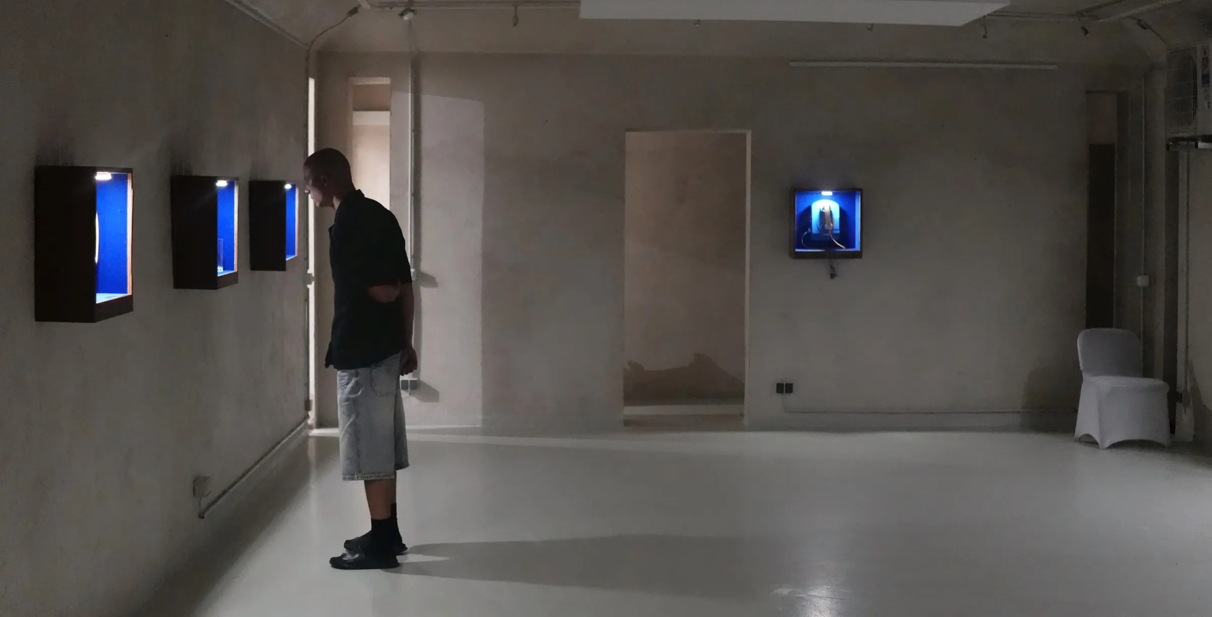Ein Betrachter beugt sich im Bunker West zu den Vitrinen
