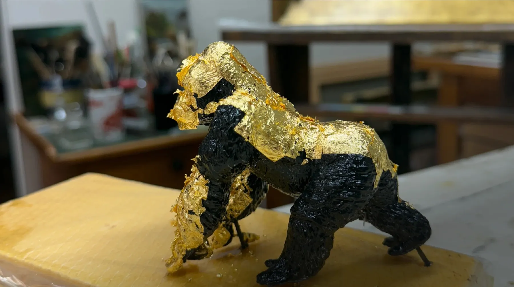 Gorilla figure, half covered in gold leaf, on the workbench