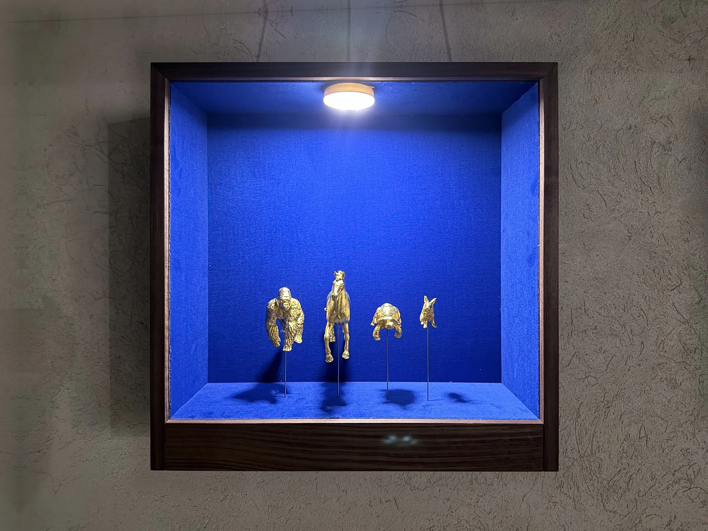 Vitrine mit vier goldenen Tieren an der Betonwand