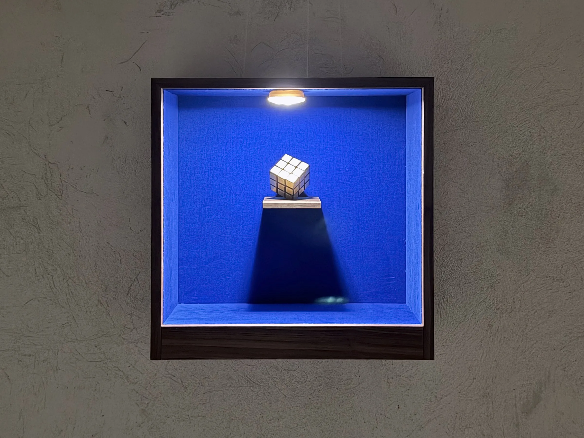 Vitrine mit goldenem Zauberwürfel an der Betonwand