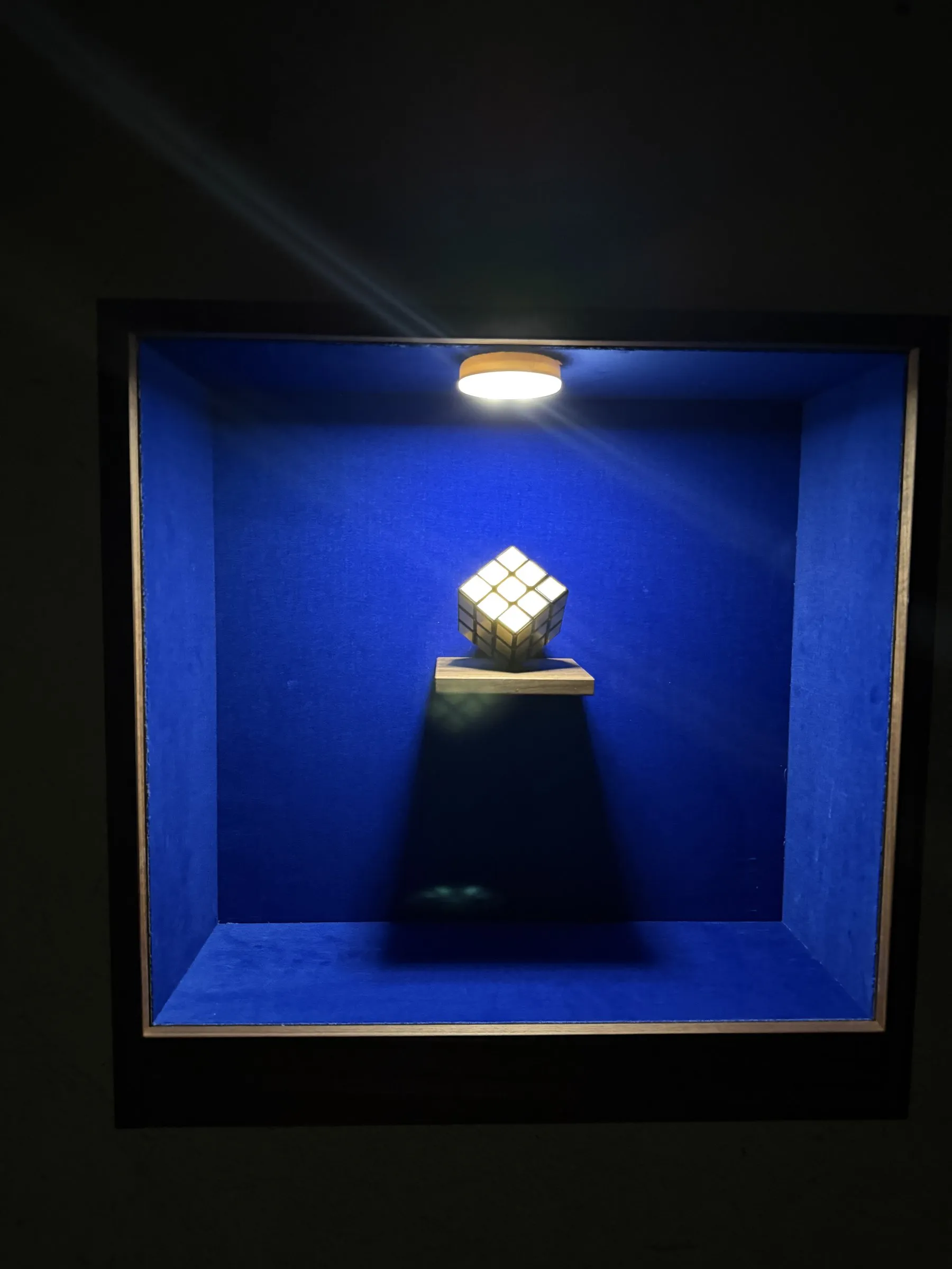 Goldener Zauberwürfel auf einem Brettchen vor blauem Samt