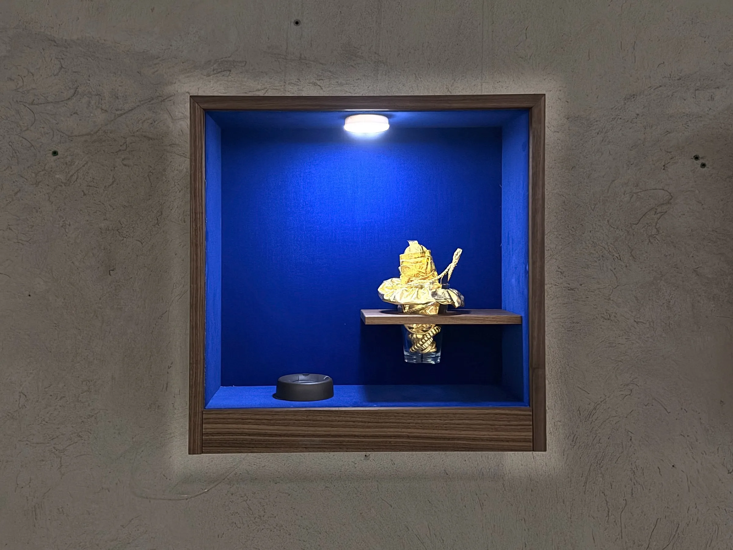 Vitrine mit goldenem Becher an der Betonwand