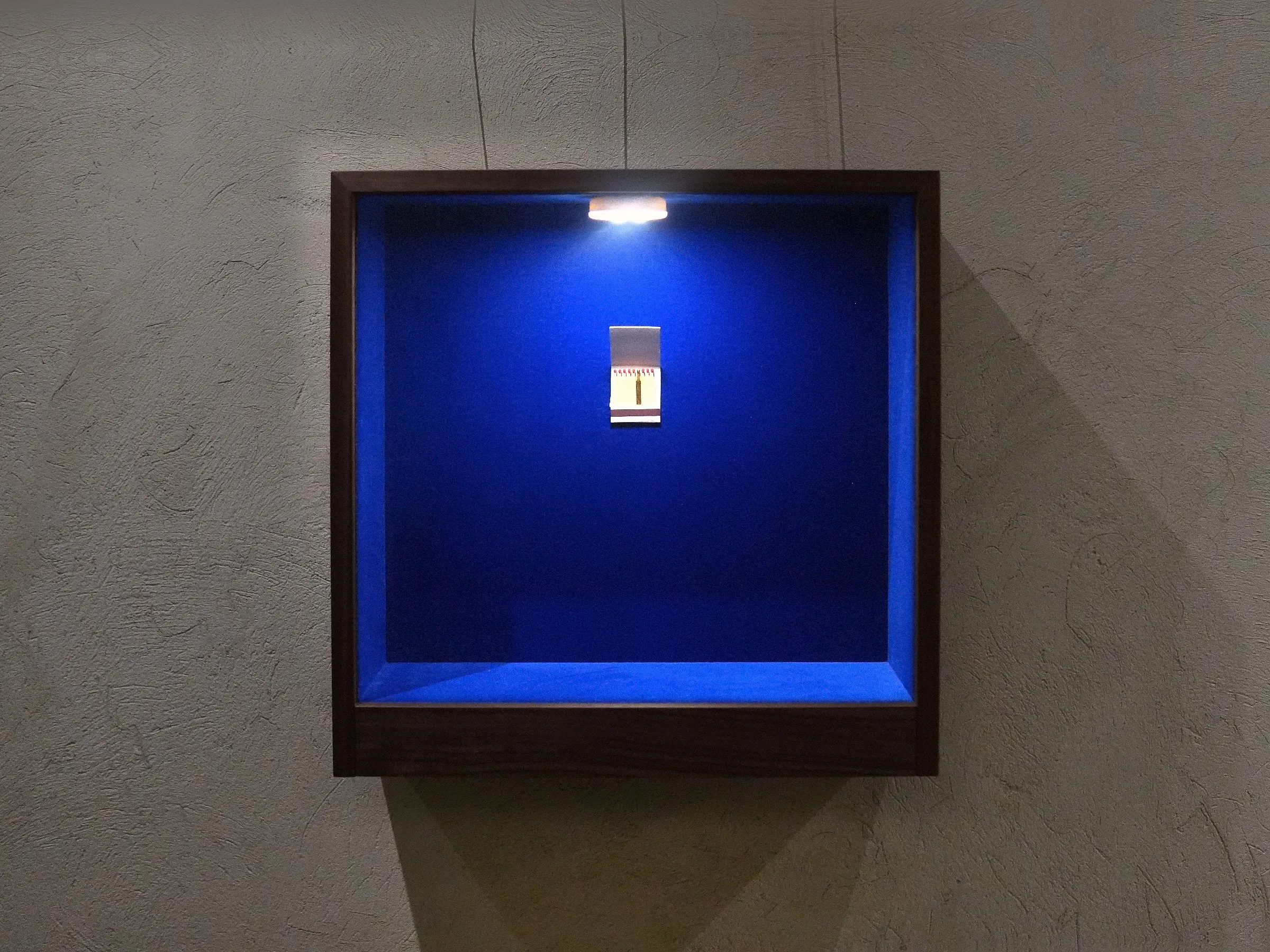 Vitrine mit Streichholzbriefchen an der hellen Wand