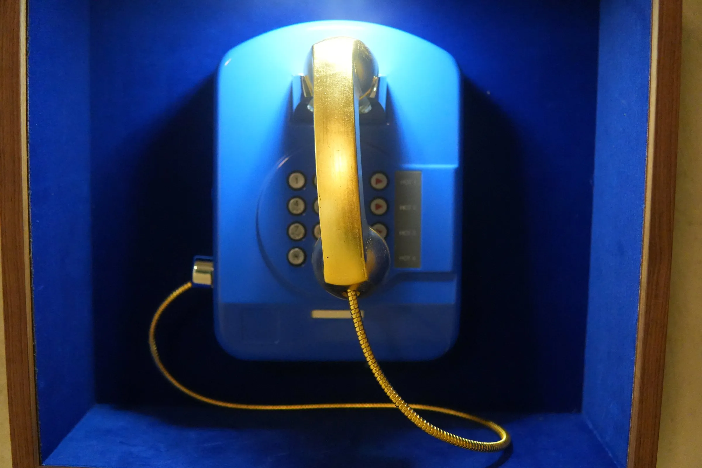 Blaues Wandtelefon mit goldenem Hörer und goldener Schnur