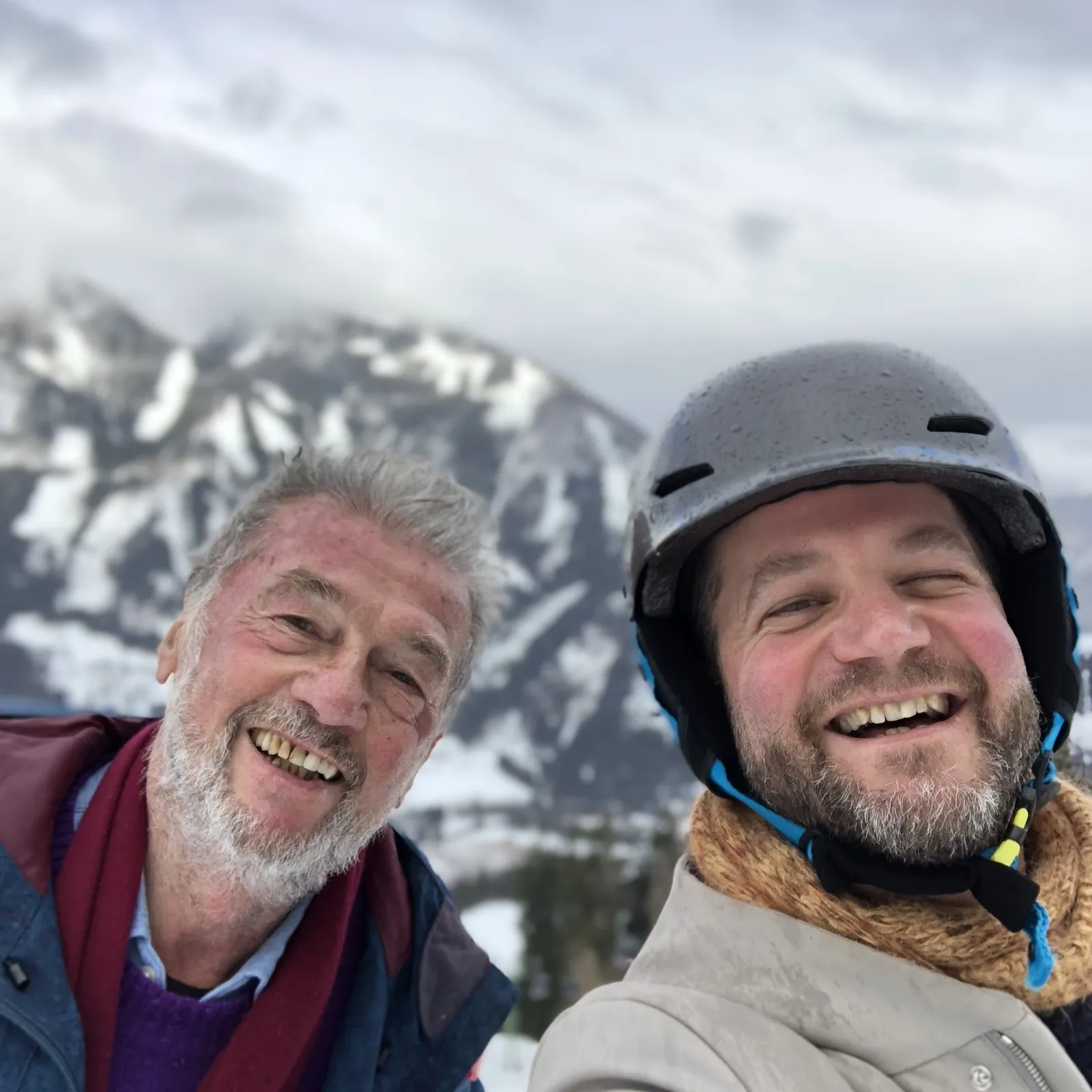 Josef und Philipp lachend beim Skifahren, Selfie vor verschneiten Bergen