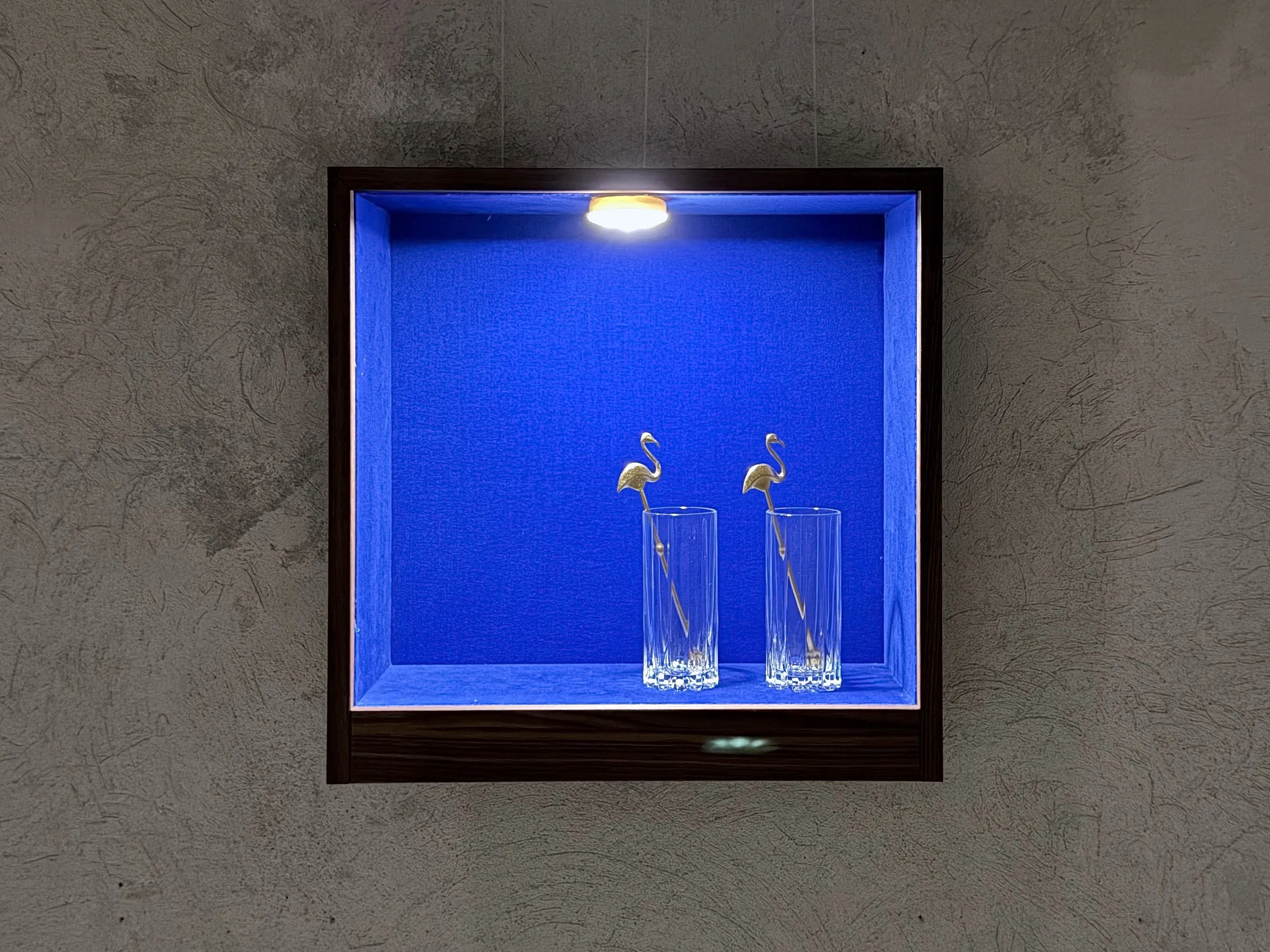 Vitrine mit zwei Gläsern an der Betonwand