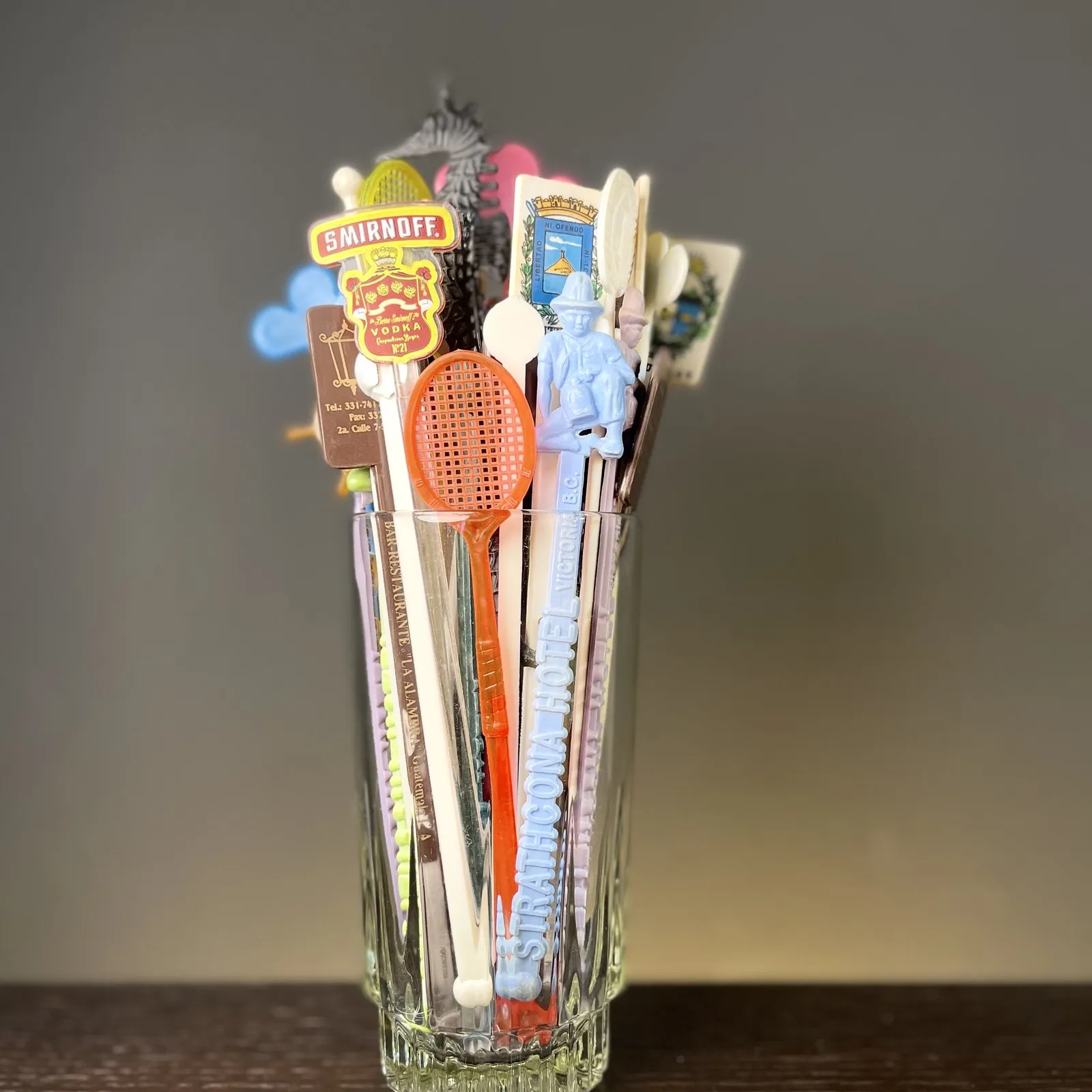 Ein Glas voller bunter Cocktailrührer auf einem Holztisch