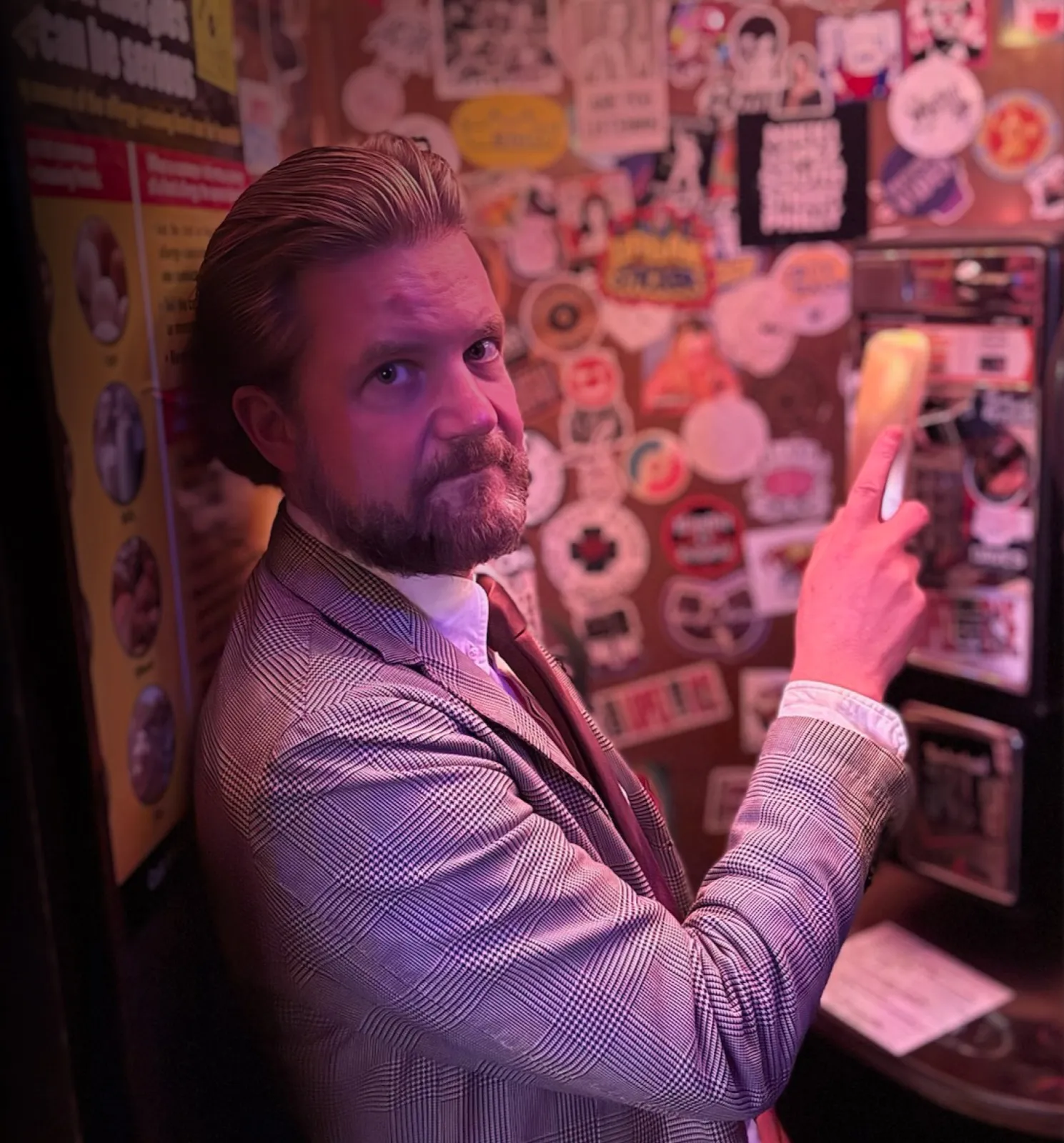 Philipp Erlach am Münztelefon vor einer Wand voller Sticker, Hand am goldenen Hörer